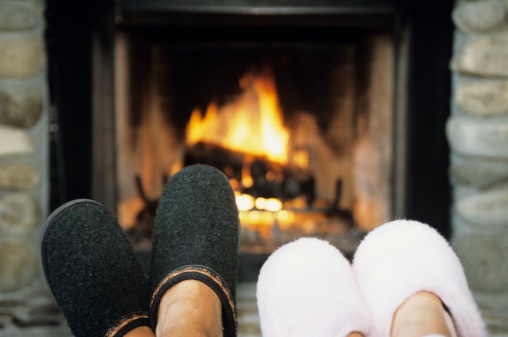 two_pairs_of_feet_wearing_slippers_in_front_of_fireplace