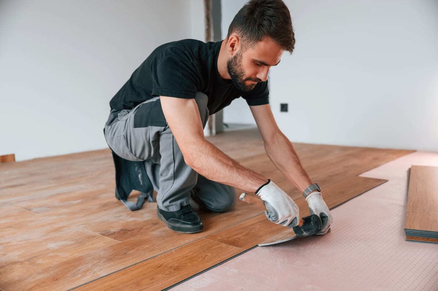 Contractor installing laminate flooring in home