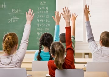 children_raising_hands_in_classroom