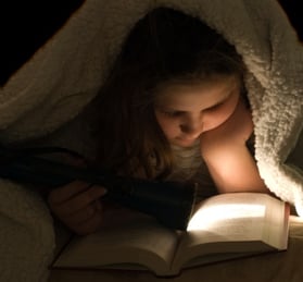 young_girl_reading_under_blanket_with_flashlight