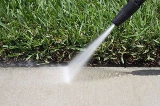 person cleaning concrete with pressure washer