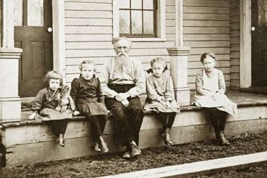 old_portrait_grandpa_sitting_on_porch_with_grandaughters
