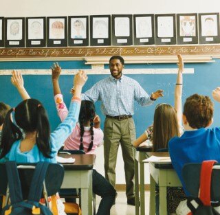 students raising hands in classrom