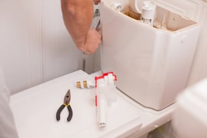 person fixing toilet tank shutterstock_1151062385