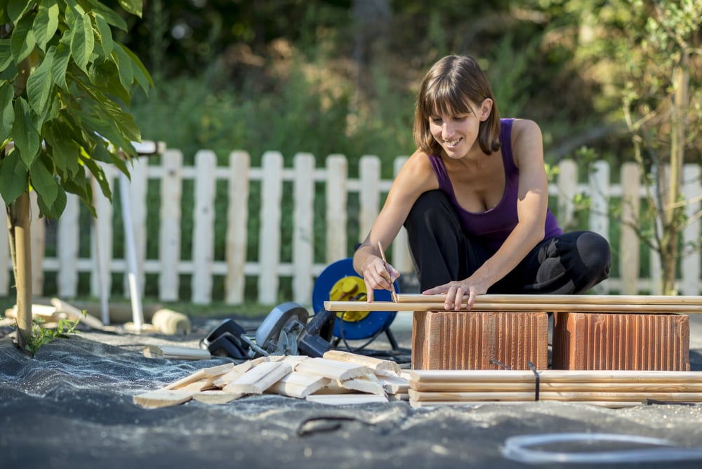 woman marking board for backyard fence project