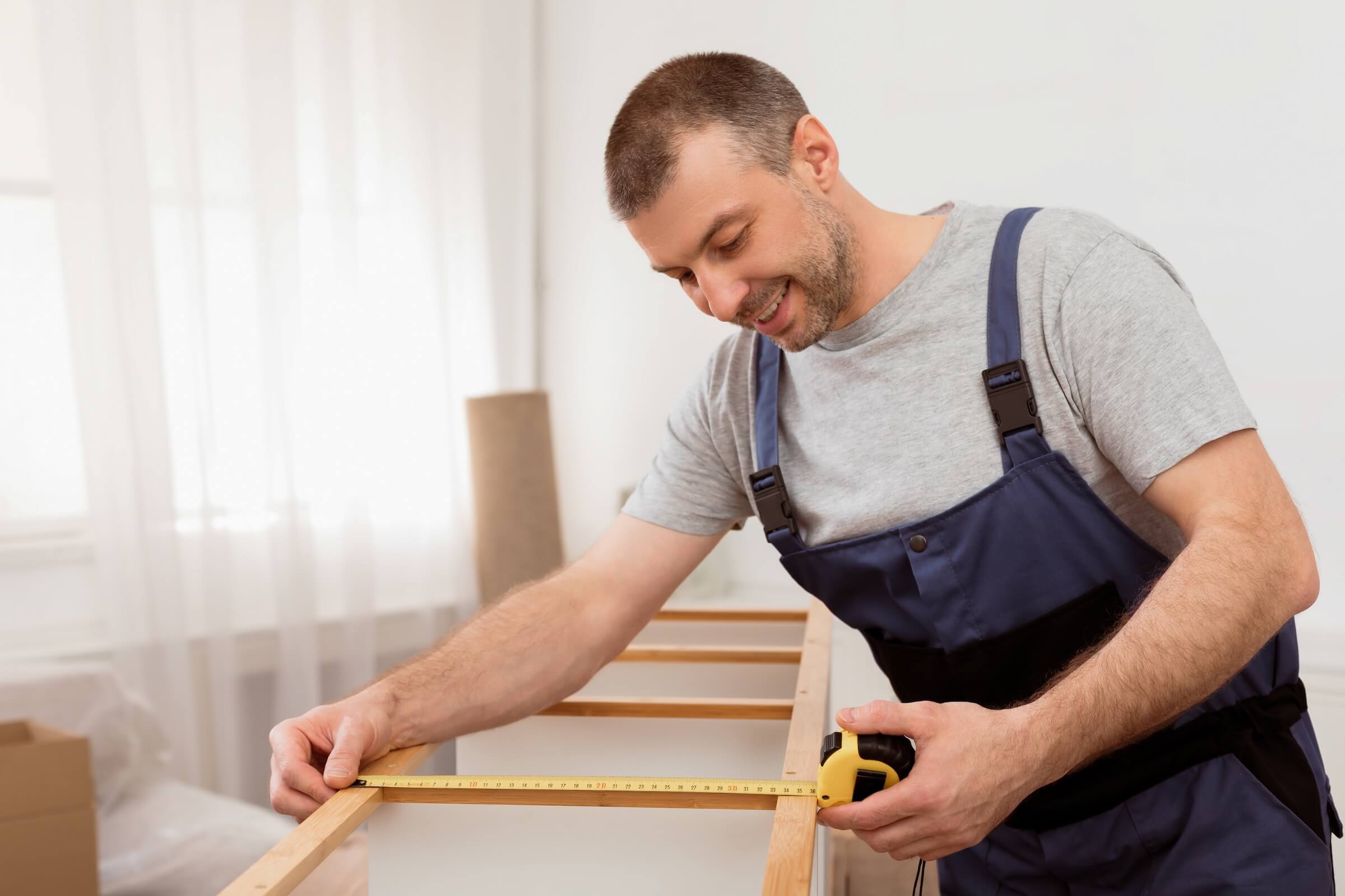 Male contractor measuring cabinets during a kitchen renovation