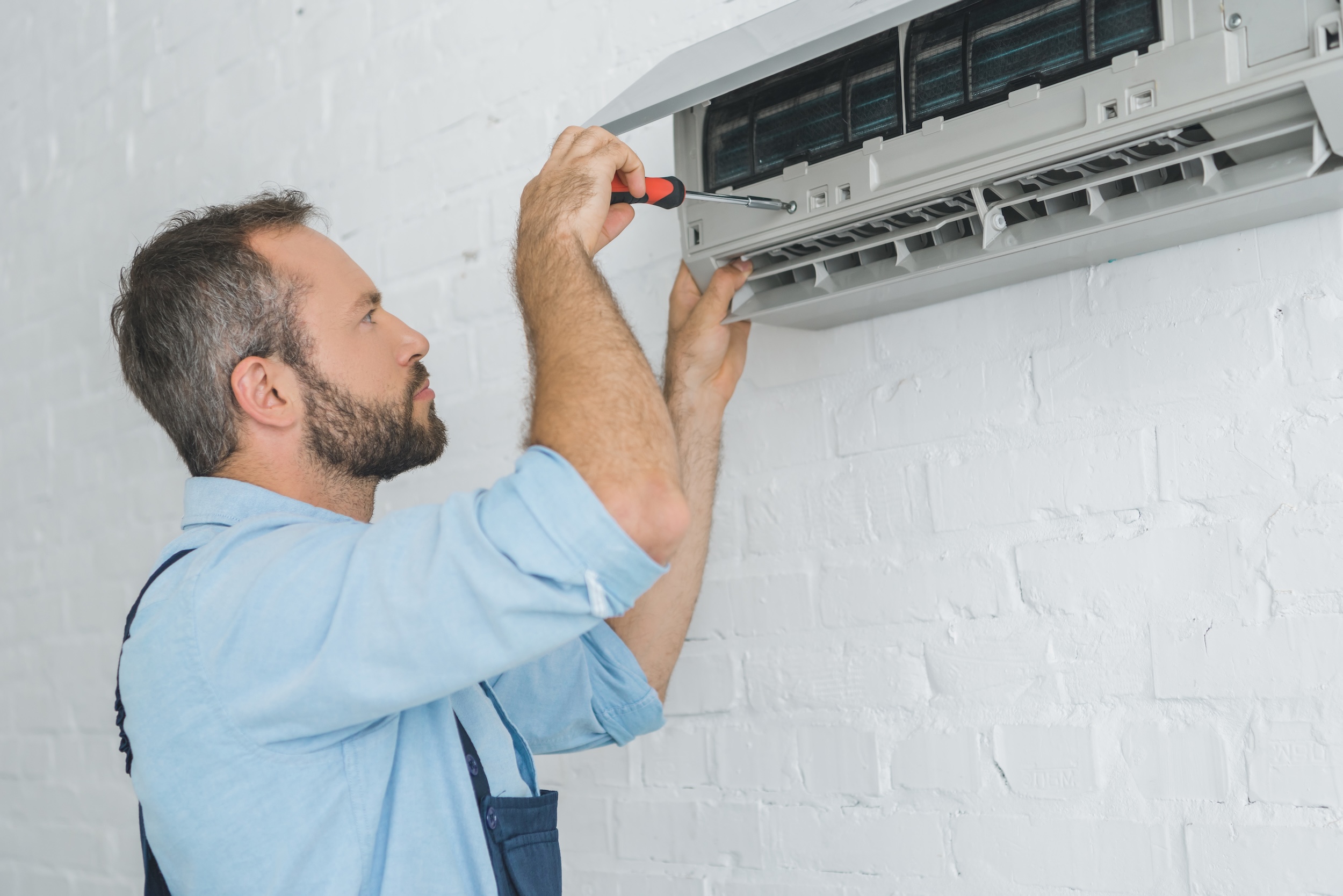 This image features a repairman working to check HVAC airflow. 