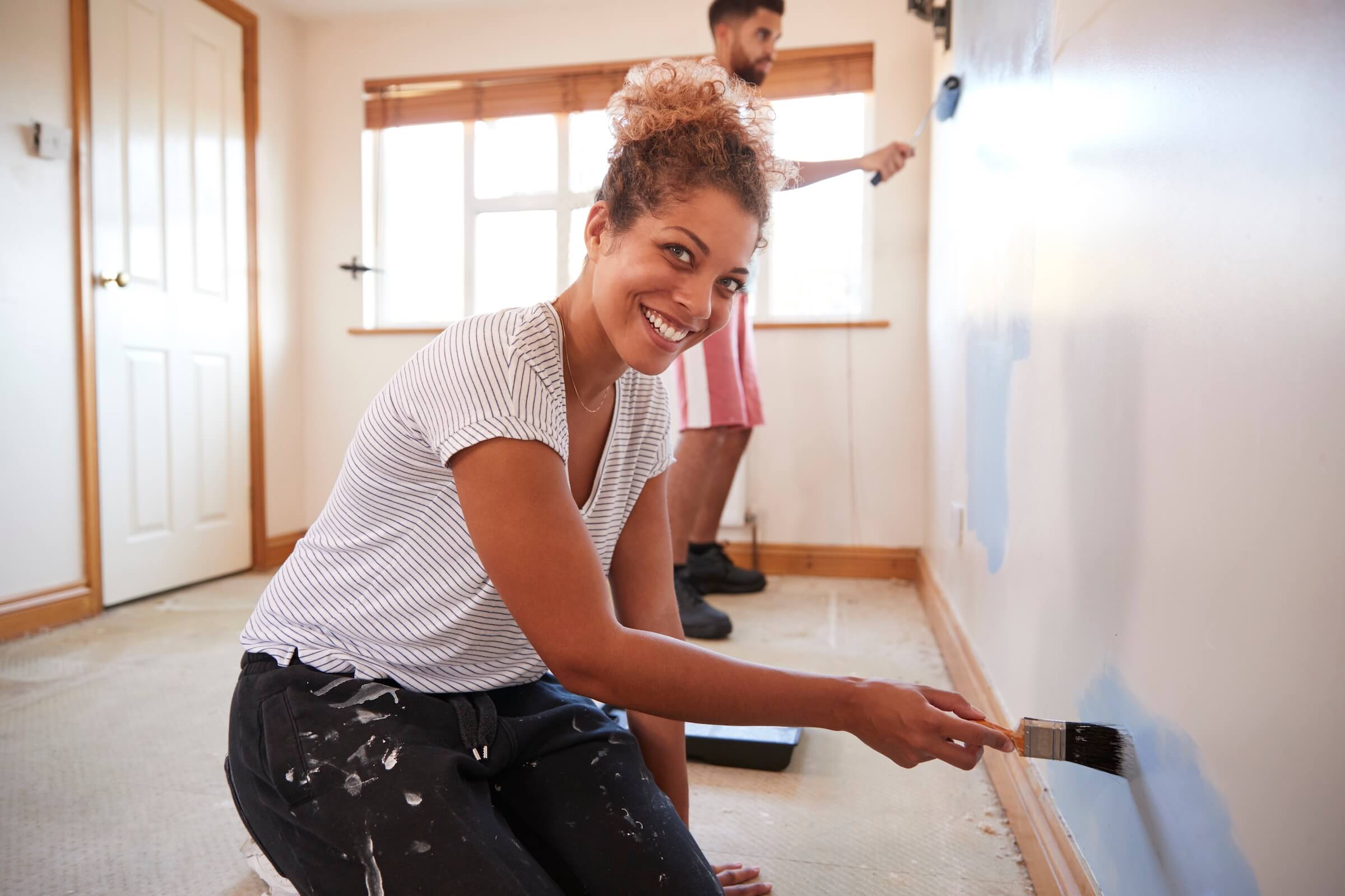 Woman painting interior room of her house with a brush